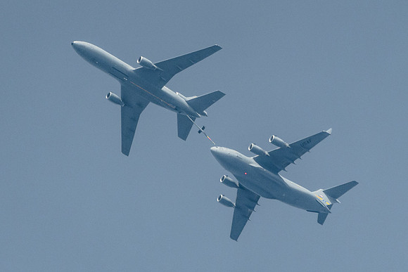 Two Military aircraft during a mid-air re-fueling procedure.  A KC-10 refueling a C-17.